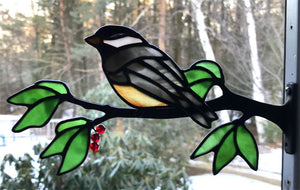 stained glass chickadee on a window frame metal branch with red berries
