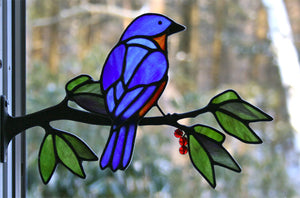 stained glass eastern bluebird on a window frame metal branch with red berries